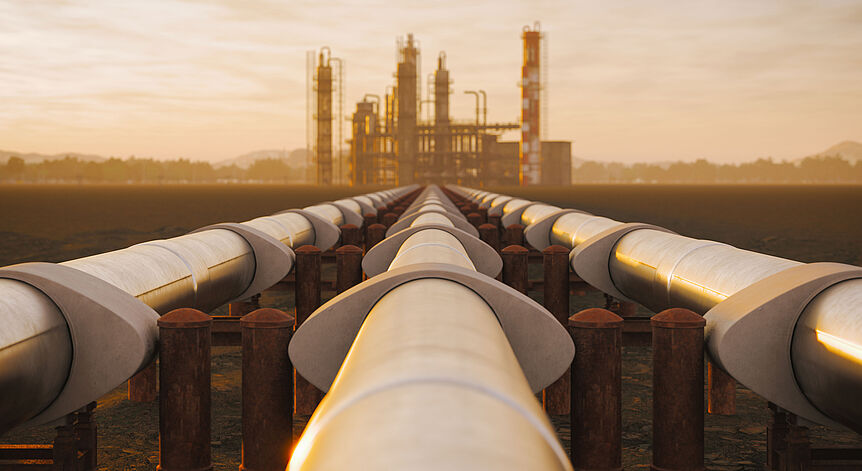 Foto von Ölpipeline mit Industriegebiet im Hintergrund in der Abendsonne