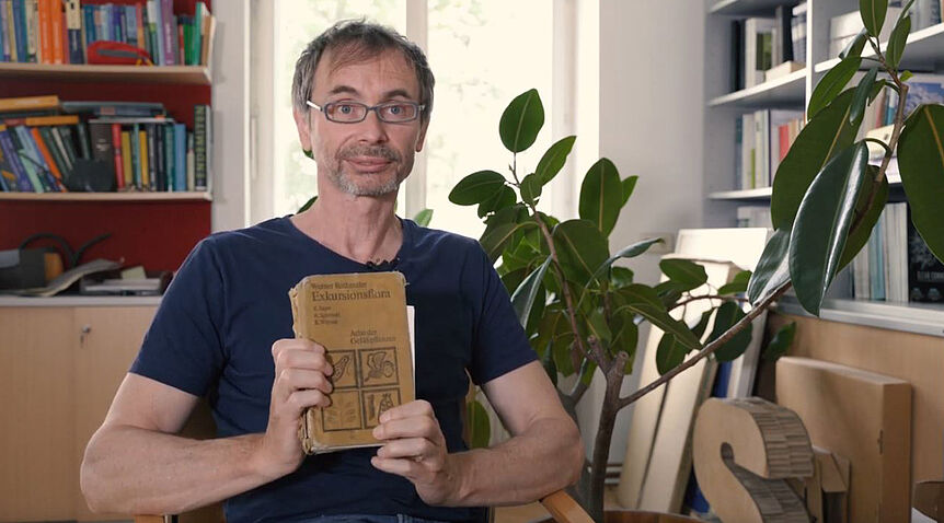 Portraitfoto von Dullinger, während er ein Buch in der Hand hält