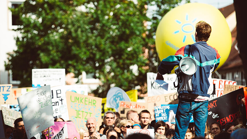 Junge Menschen demonstrieren mit Schildern gegen die Klimakrise