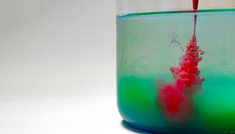 Symbolfoto: Eingefärbte Chemikalien breiten sich in einem Glas Wasser aus.  